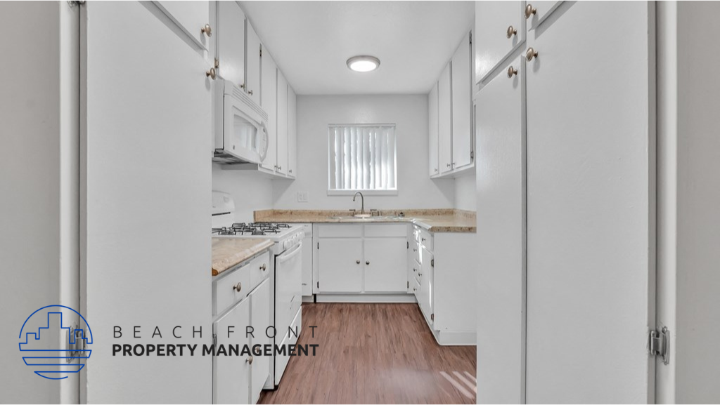 a white kitchen with white cabinets and a window