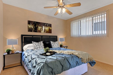 A bedroom with a bed, nightstands, and a ceiling fan.