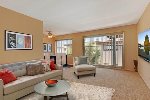 A living room with a grey couch, a round table, and a painting on the wall.