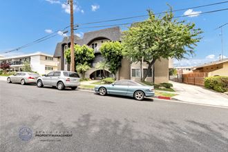 a view from the street of the home with cars parked in front of it