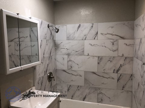 A marble tiled bathroom with a shower and a bathtub.