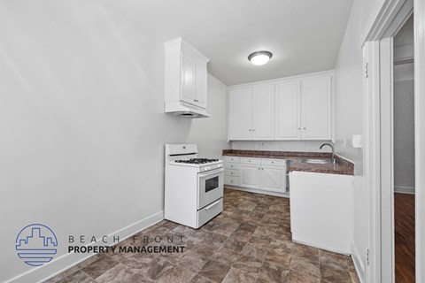 A kitchen with white cabinets and a stove top oven.