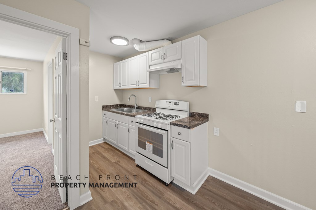 a kitchen with white cabinets and a stove and a sink