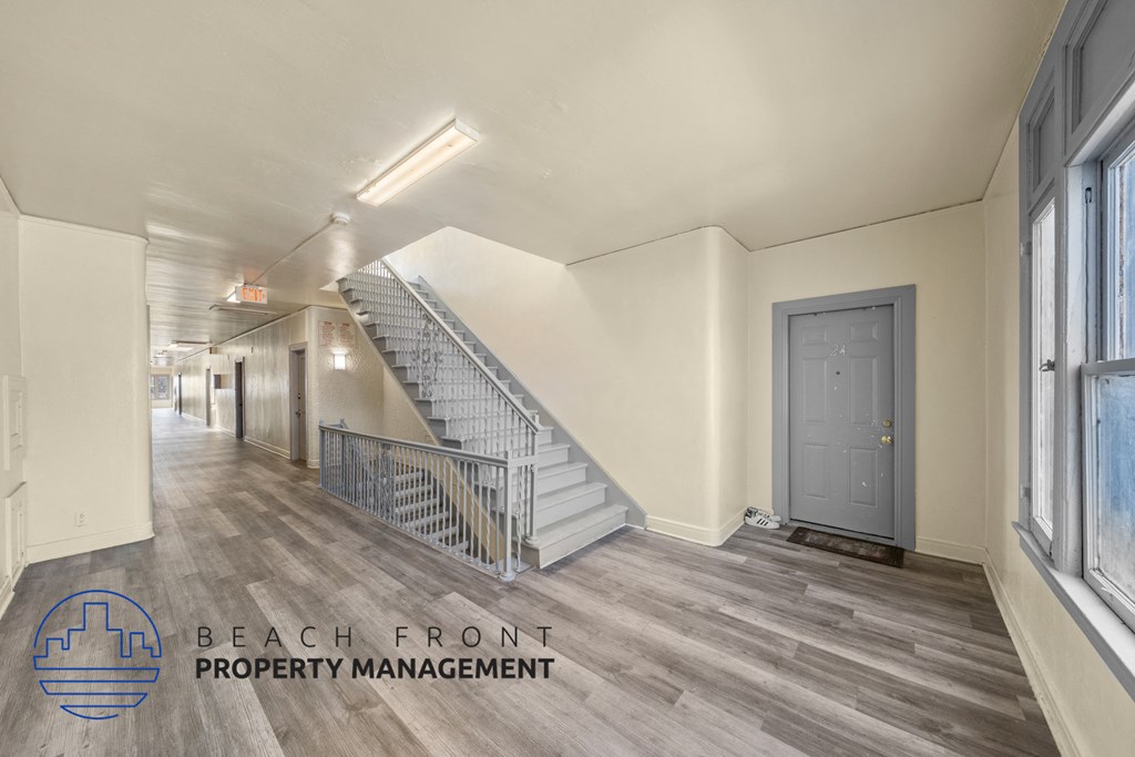 a room with a staircase and a door and a hallway with windows and a floor