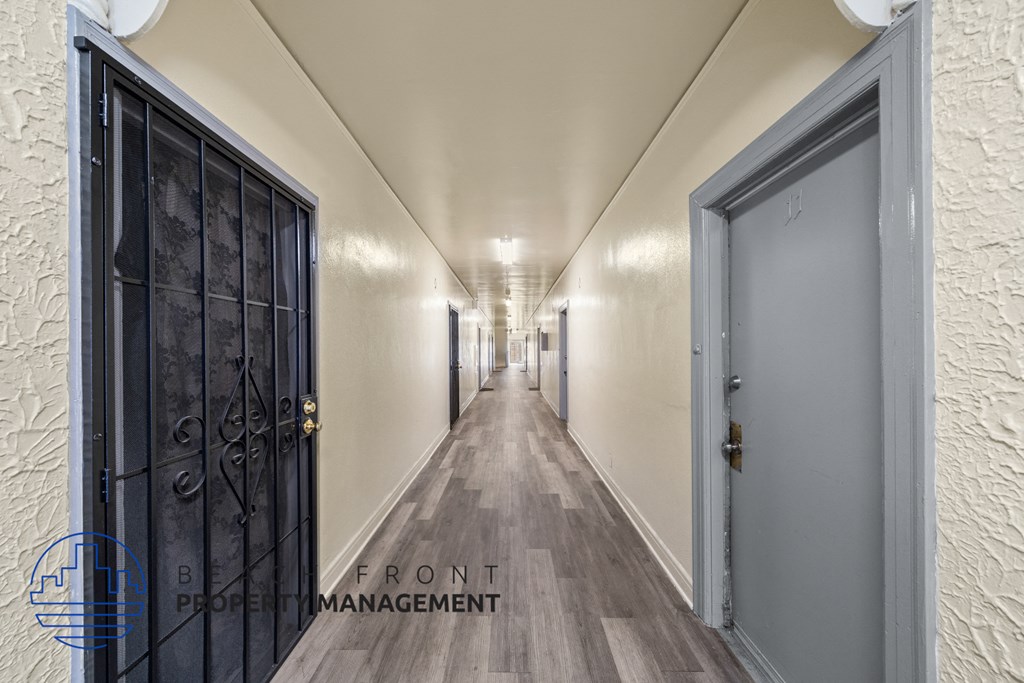 a long corridor with doors and white walls and wooden floors
