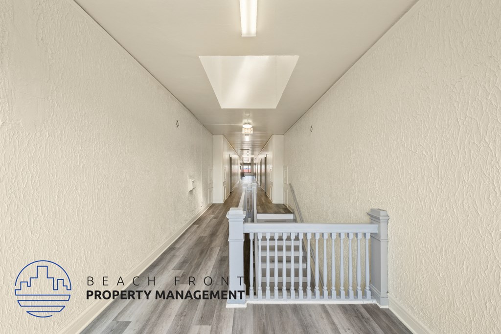 a long hallway with white walls and a white railing and a hallway with wood floors