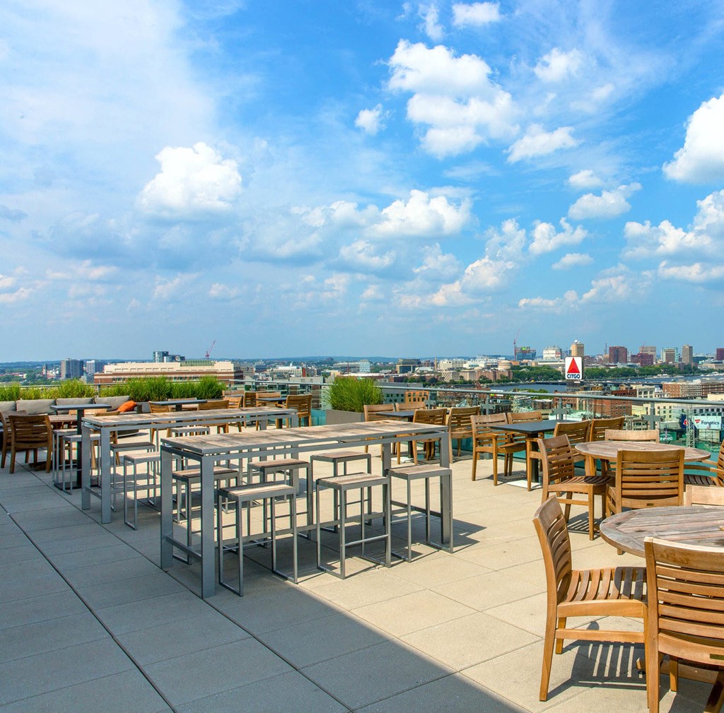 A rooftop patio with tables and chairs overlooking a city skyline.