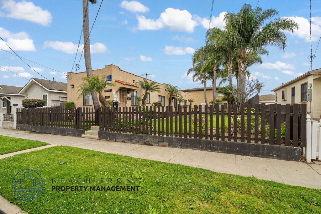 A black fence surrounds a house with a sign that says Beachfront Property Management.