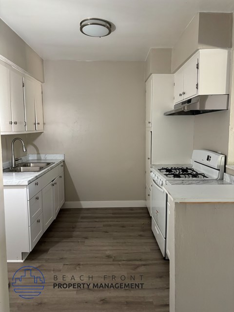 A kitchen with white cabinets and a stove top oven.