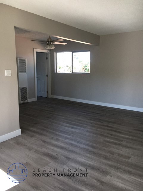 an empty living room with wood floors and a ceiling fan