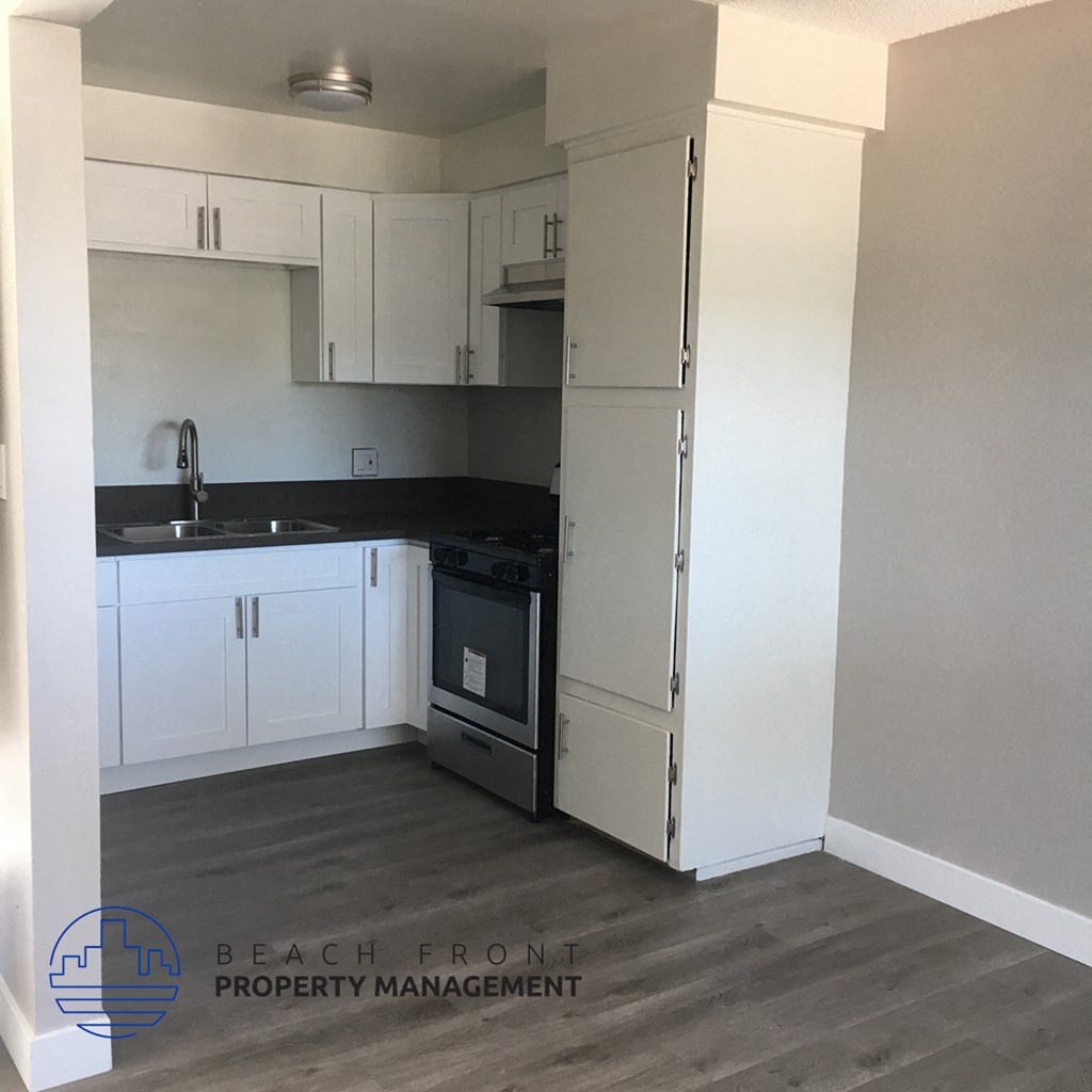 a kitchen with white cabinets and a sink and a refrigerator