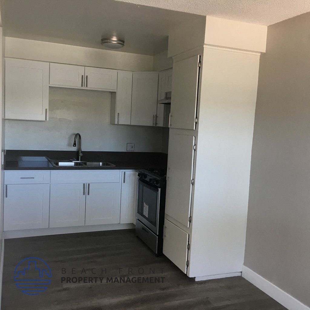 a kitchen with white cabinets and a sink and a refrigerator