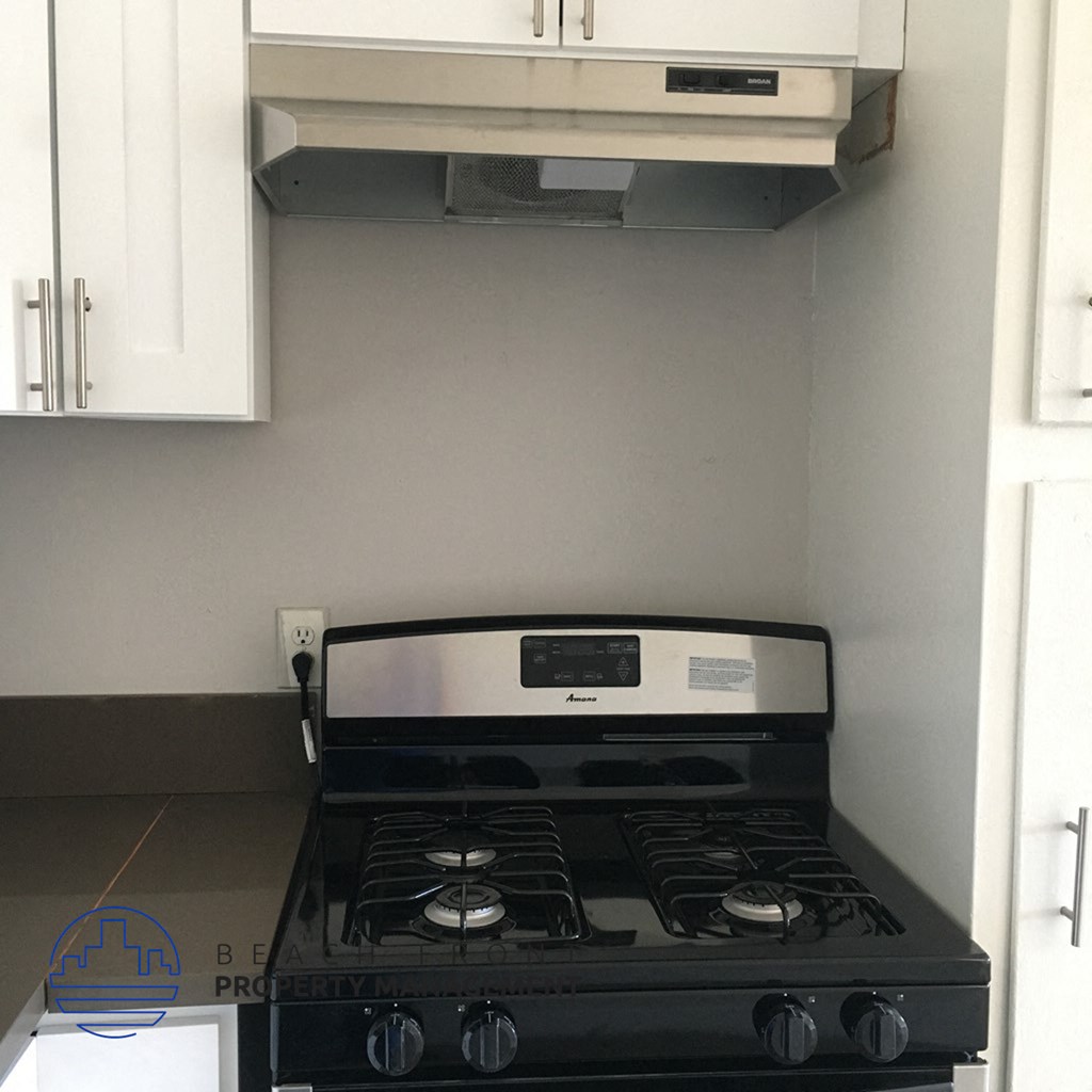 a black stove top oven in a kitchen with white cabinets
