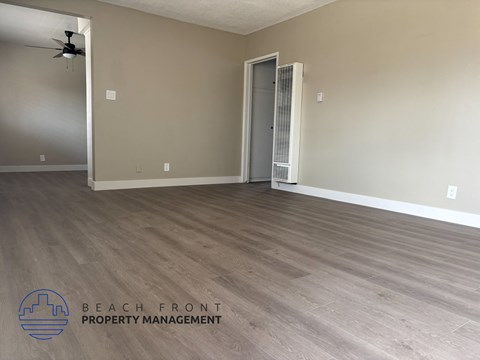 A room with wooden flooring and a closed door is shown.