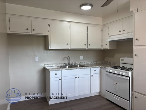A kitchen with white cabinets and a stove top oven.