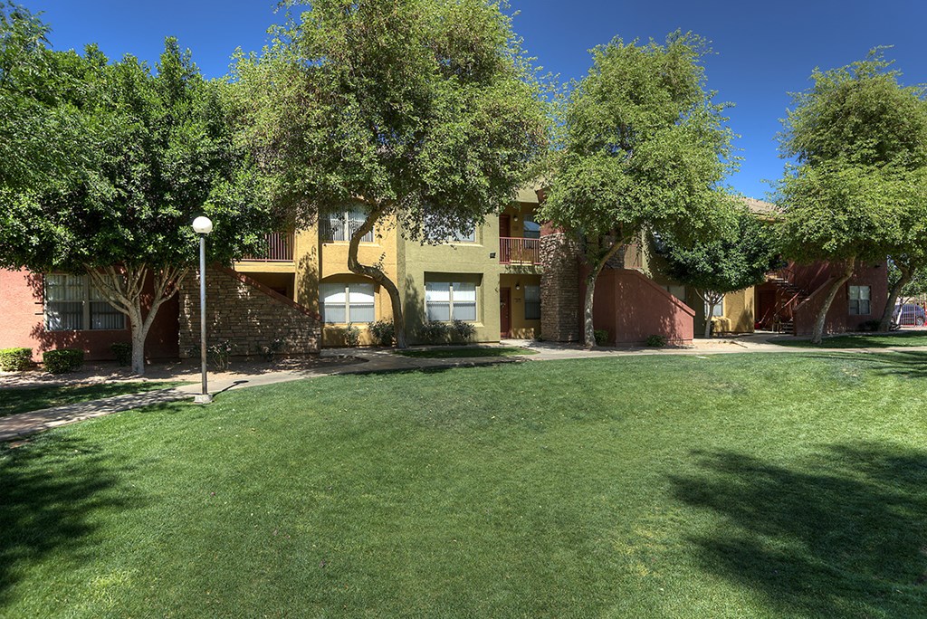 a large yard in front of a building with trees