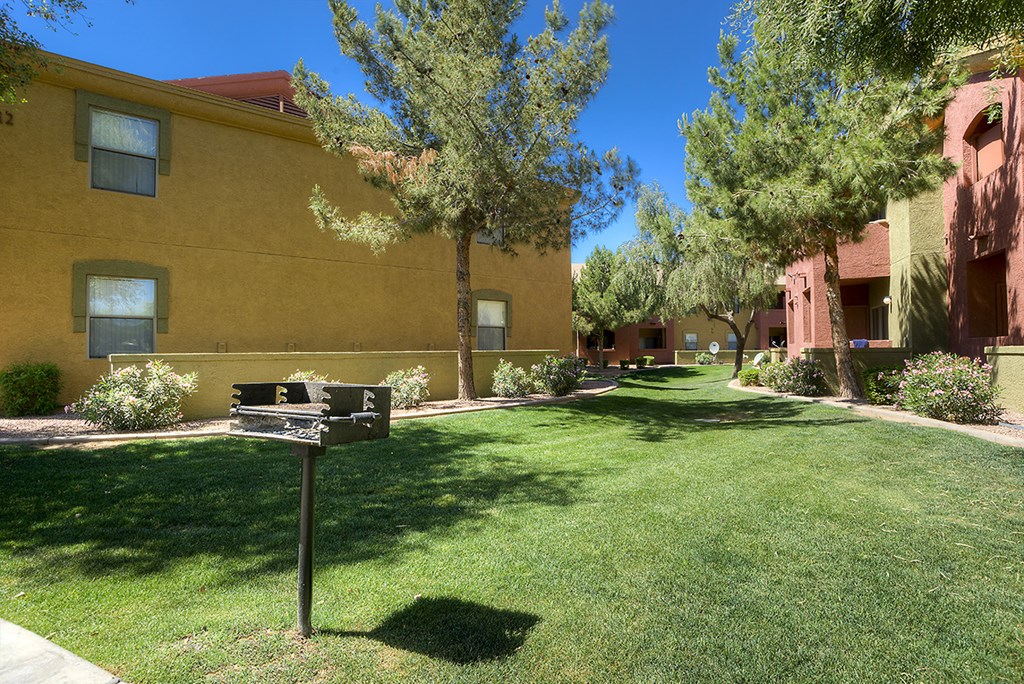 a yard in front of a building with a grill