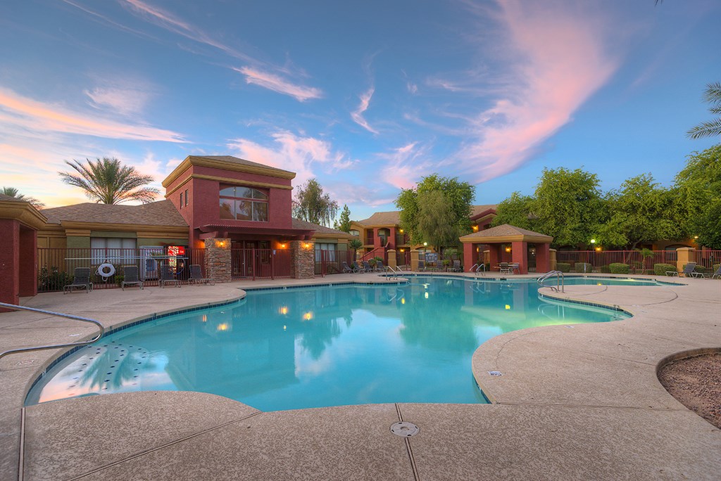 a swimming pool in front of a hotel with a blue sky