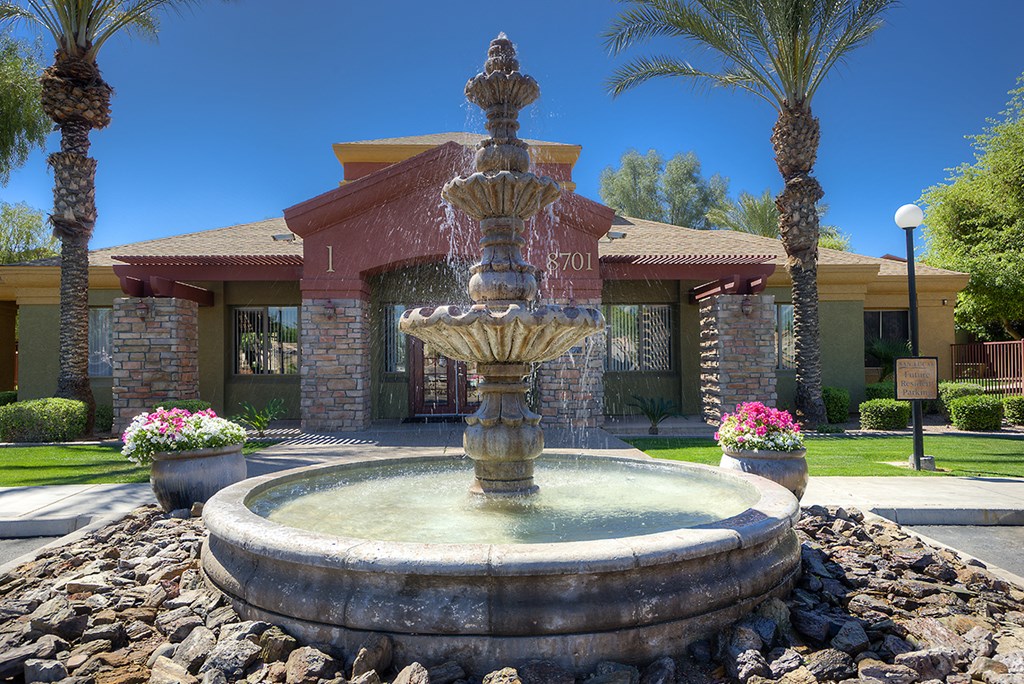 a fountain in front of a building with palm trees