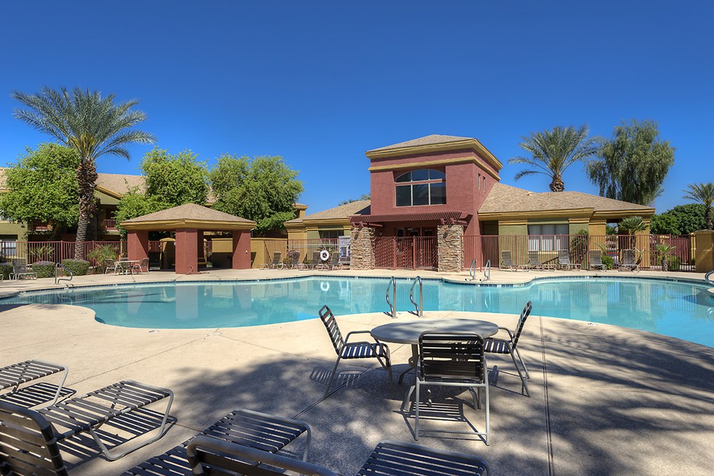 a swimming pool with chairs and tables in front of a building