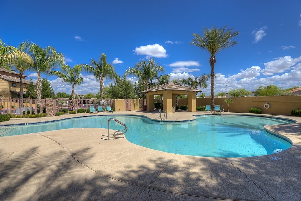 a swimming pool with a gazebo and palm trees