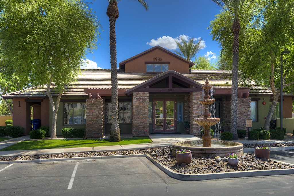 the front of a house with a fountain in front of it