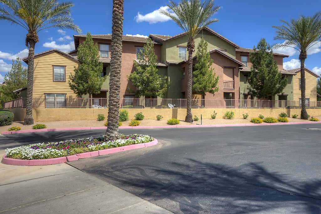 an empty street in front of an apartment building with palm trees