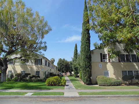 a sidewalk lined with apartment buildings and trees