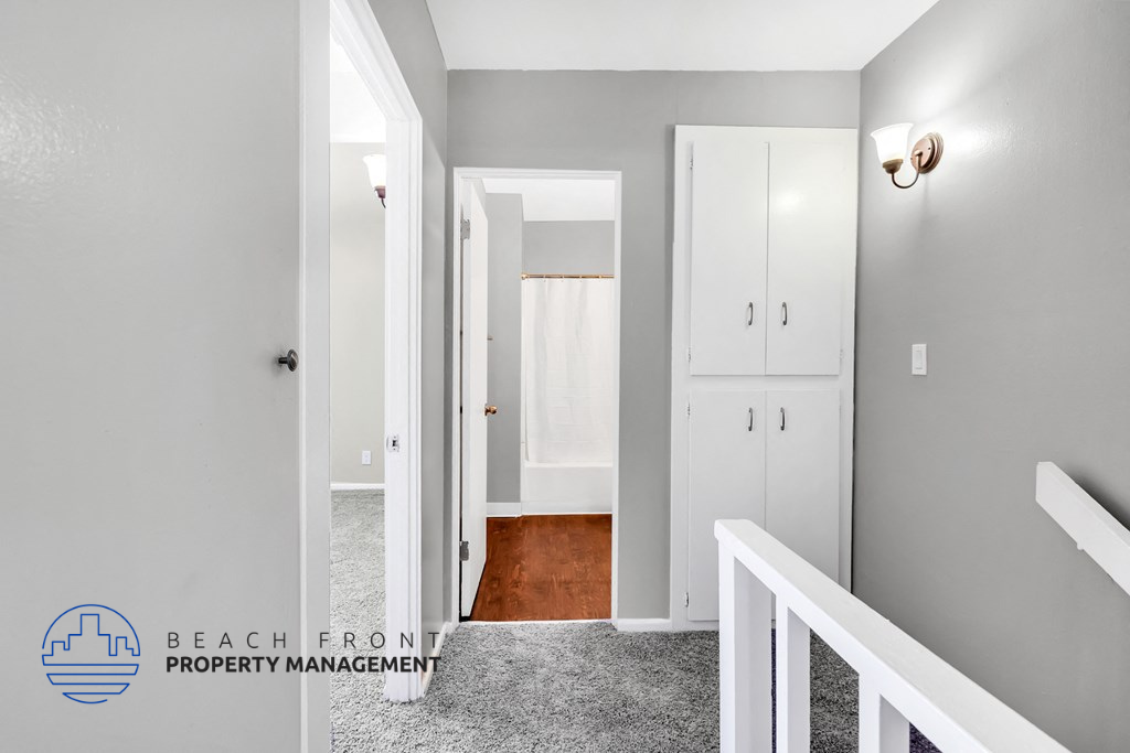 a bedroom with white closets and a hallway with a staircase