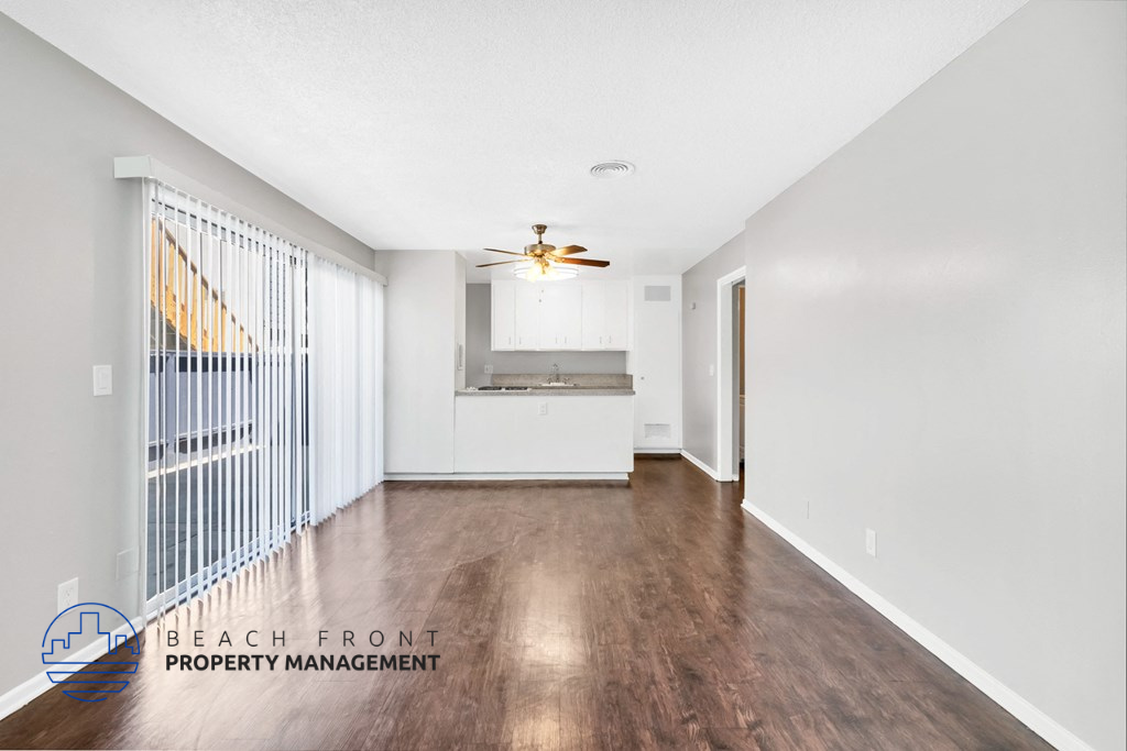 a living room and kitchen with wood flooring and a ceiling fan