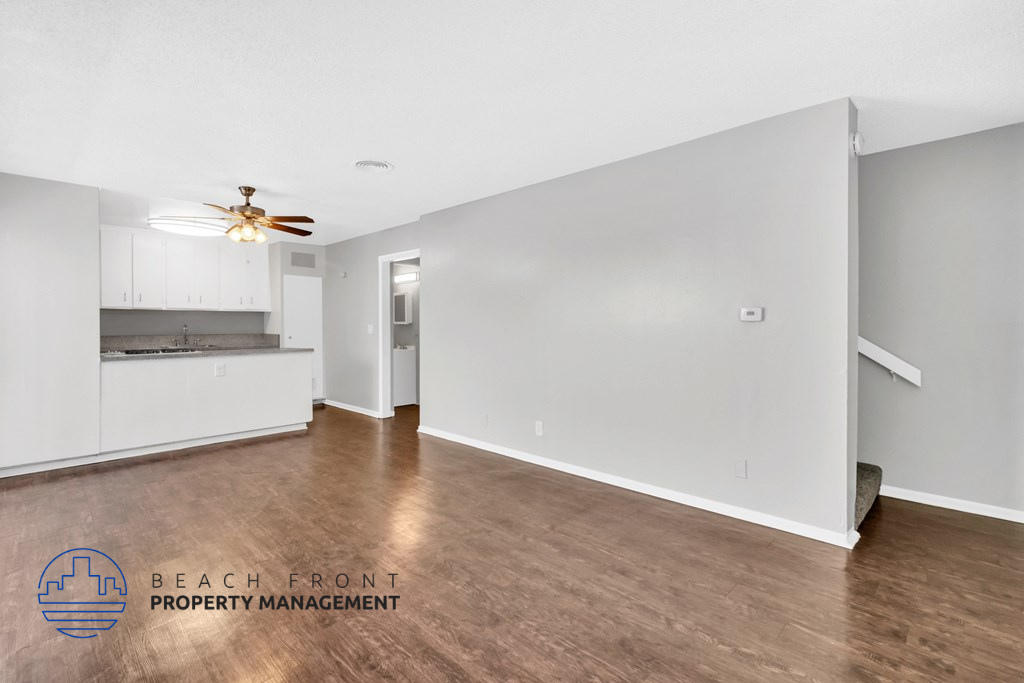 a living room and kitchen with wood flooring and a ceiling fan