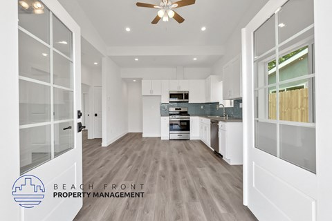 A spacious kitchen with white cabinets and a ceiling fan.
