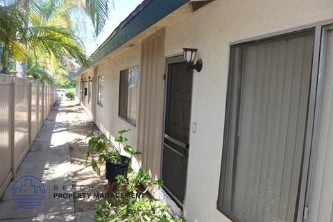 A sunny day at the BE Property Management building with a row of houses and plants.