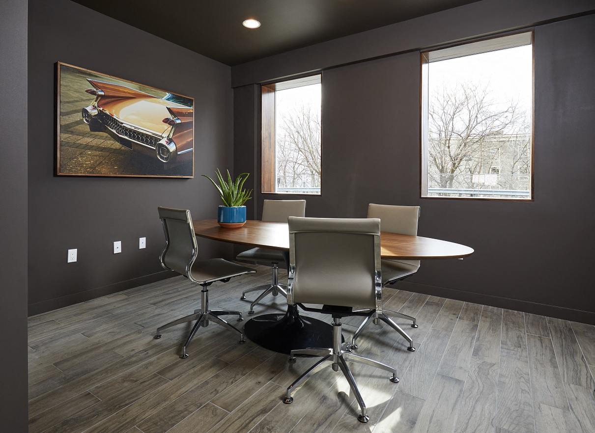 a conference room with a table and chairs and a painting on the wall