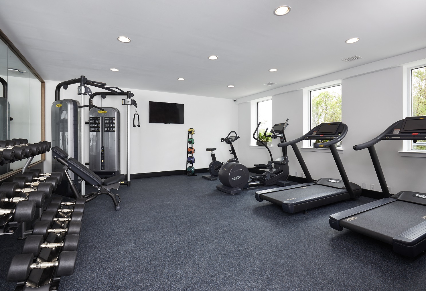two treadmills and other exercise equipment in a gym with windows