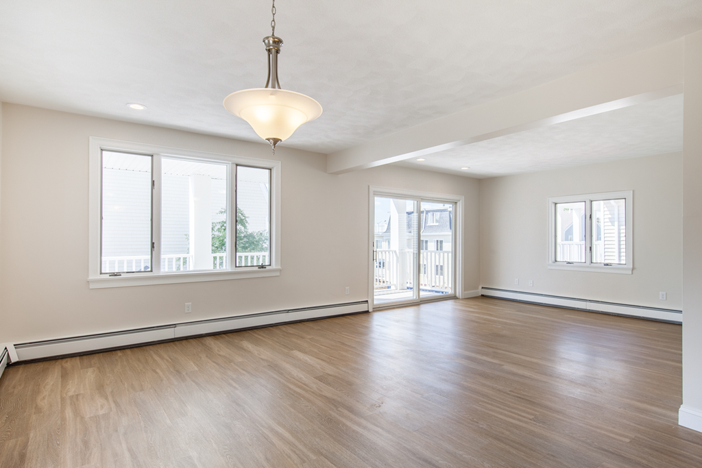 an empty living room with wood flooring and a large window
