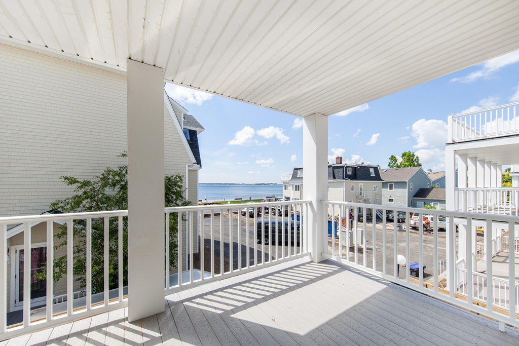 a view of the ocean from the balcony of a house with white railings