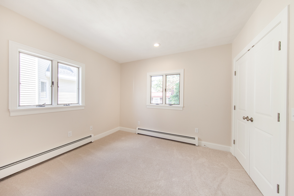 an empty bedroom with two windows and a door