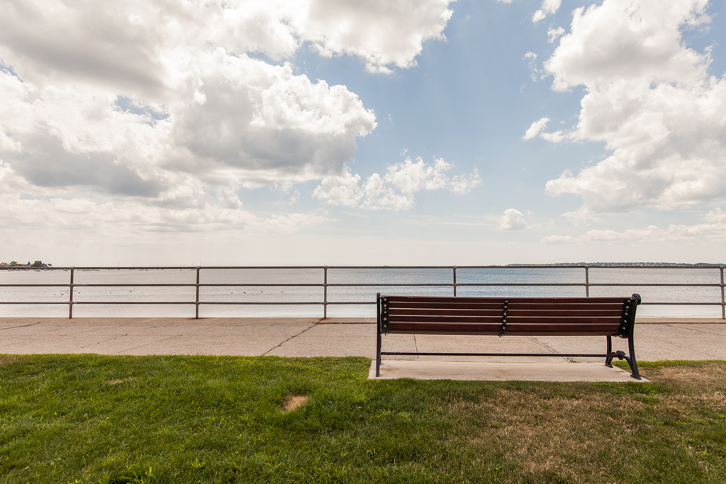a park bench overlooking the water on a cloudy day