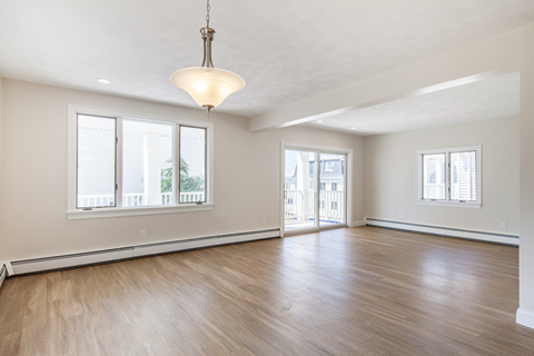 an empty living room with wood flooring and a large window