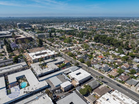 An aerial view of a city with a large building that has a pool in the foreground.