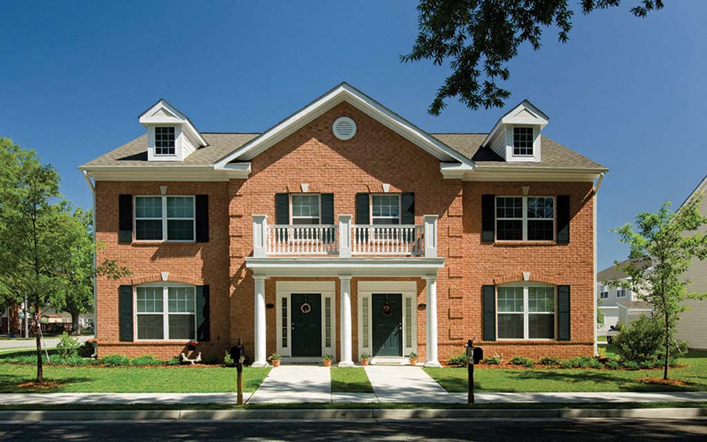 a red brick house with a balcony on a street