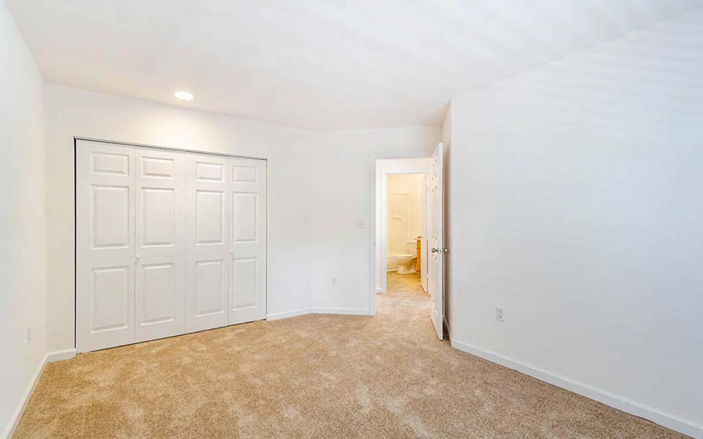an empty bedroom with a closet and a white door