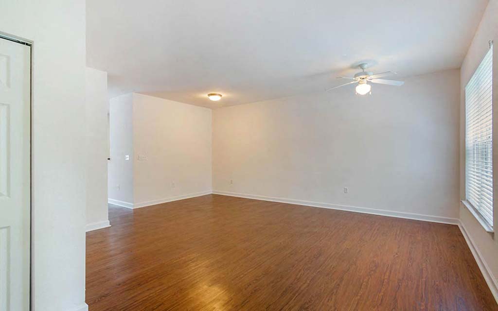 an empty living room with wood floors and a ceiling fan