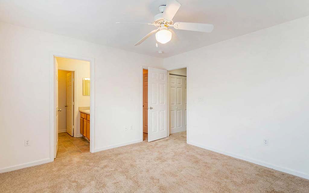 an empty living room with a ceiling fan and a closet