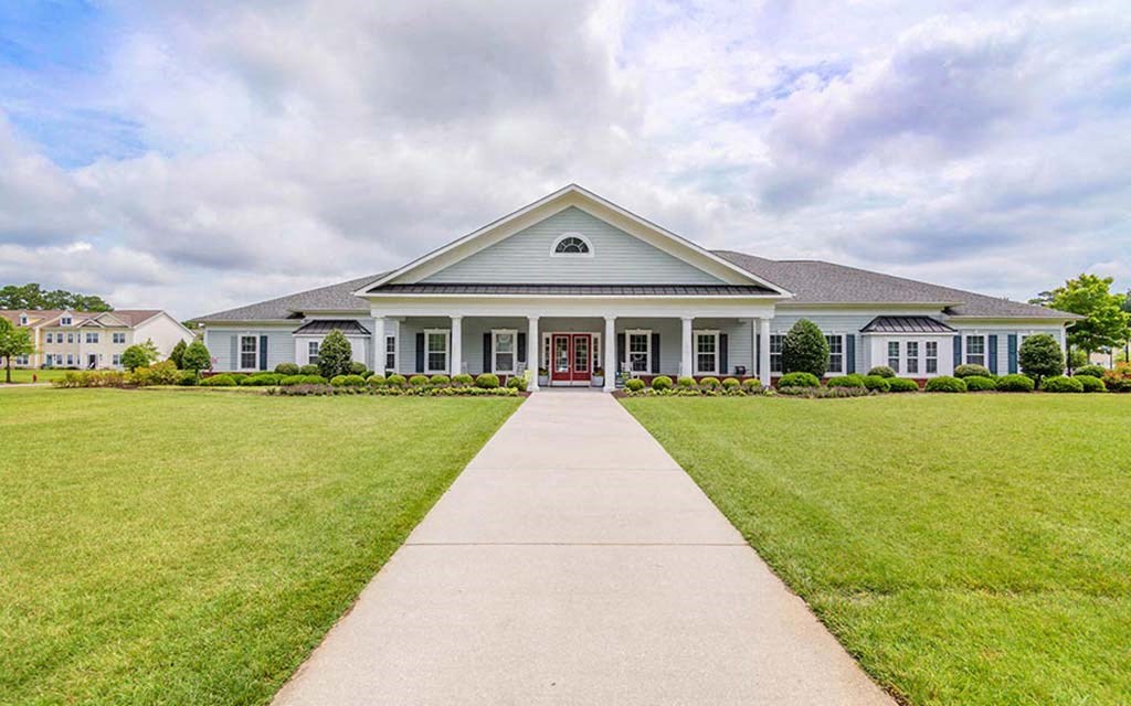 the front of a house with a walkway and grass