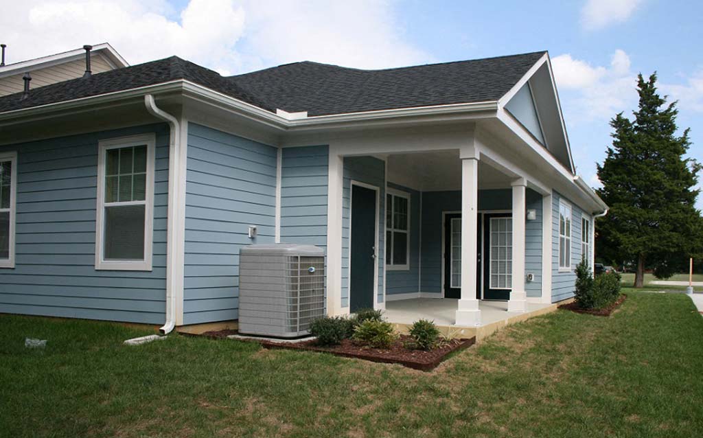 a blue house with a storm fan in the front yard