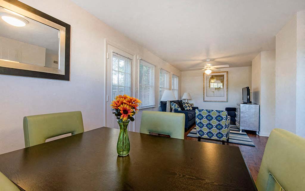 a dining room table with a vase of flowers