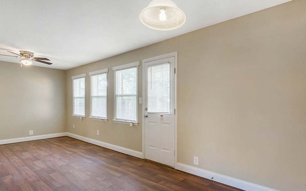 an empty living room with a door and a ceiling fan