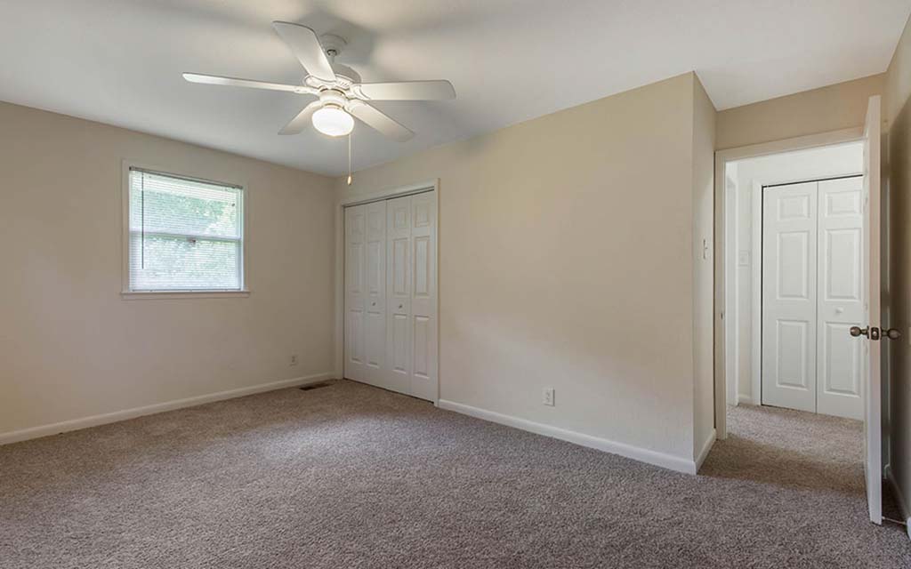 an empty bedroom with a ceiling fan and a closet